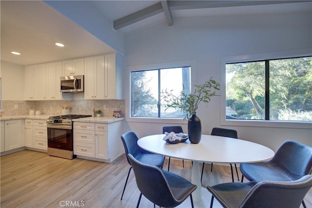 kitchen featuring lofted ceiling with beams, tasteful backsplash, appliances with stainless steel finishes, and white cabinets