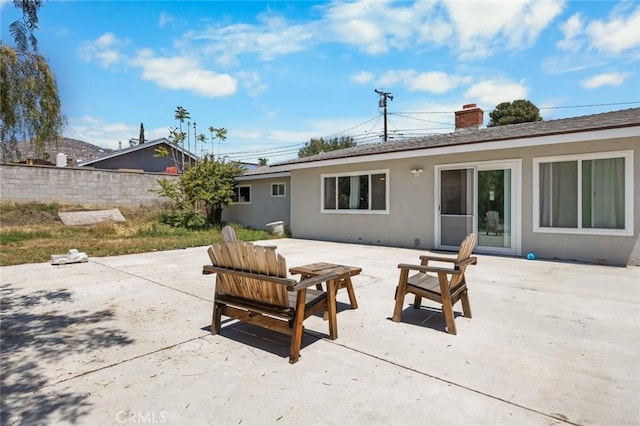 11911 Ivy Ln, Moreno Valley, CA 92557 - rear view of house with a patio area, stucco siding, a chimney, fence, and a shingled roof