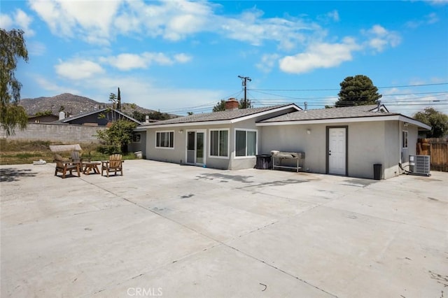 11911 Ivy Ln, Moreno Valley, CA 92557 - back of house featuring stucco siding, central air condition unit, fence, a patio area, and a fire pit