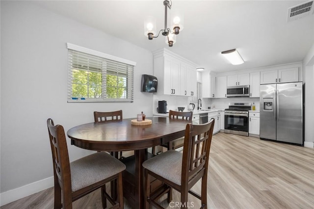 11911 Ivy Ln, Moreno Valley, CA 92557 - dining room with light wood finished floors, baseboards, and a chandelier