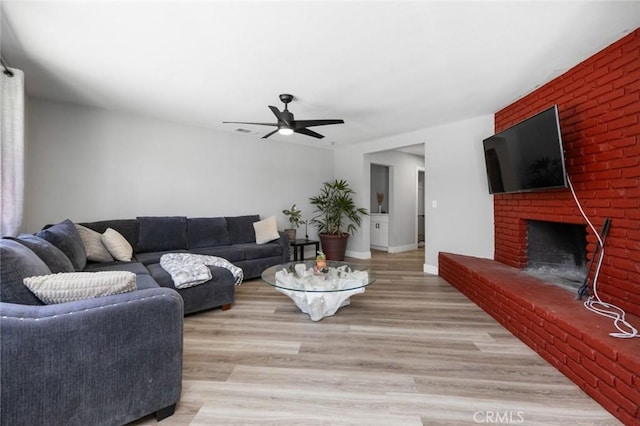 11911 Ivy Ln, Moreno Valley, CA 92557 - living room featuring a brick fireplace, ceiling fan, light wood finished floors, and baseboards