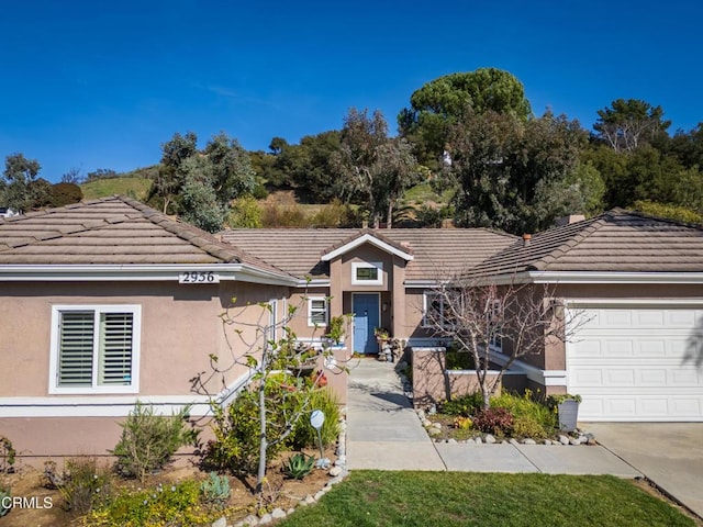 ranch-style home with stucco siding, a tiled roof, and a garage