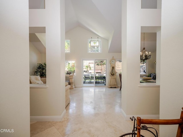 hall with an inviting chandelier, high vaulted ceiling, and baseboards