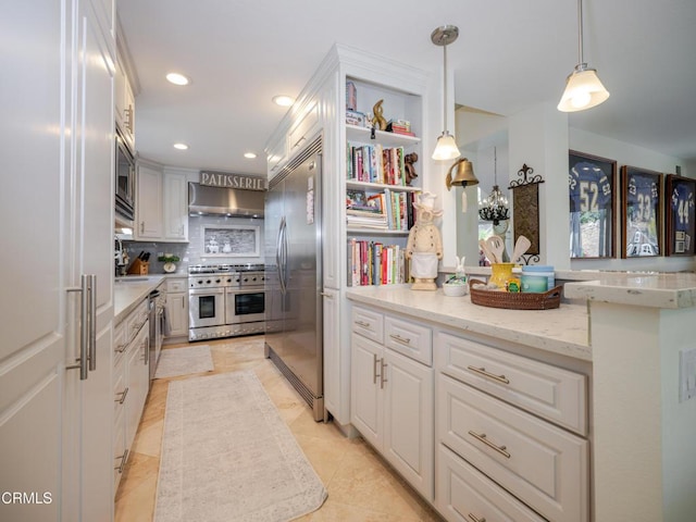 kitchen with recessed lighting, hanging light fixtures, built in appliances, white cabinetry, and wall chimney exhaust hood