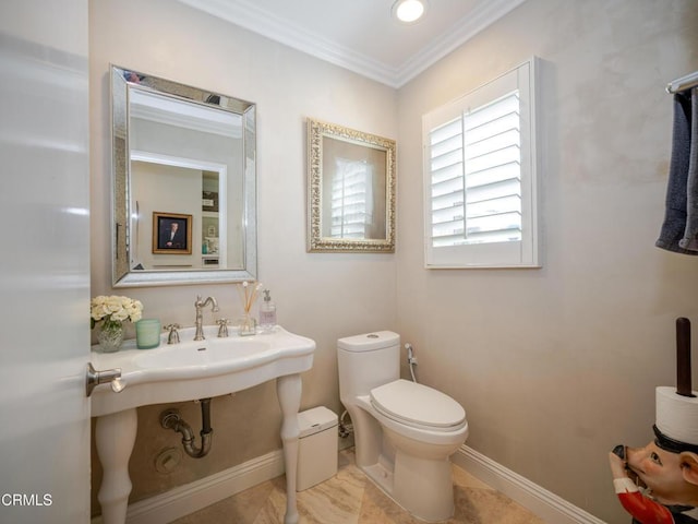 bathroom featuring a sink, toilet, baseboards, and ornamental molding