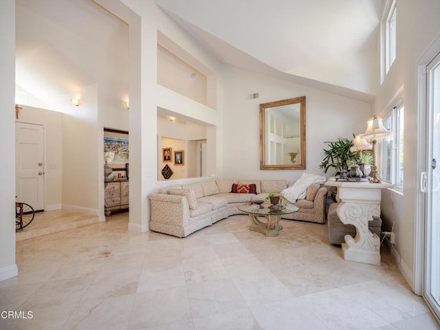 living area featuring high vaulted ceiling and baseboards