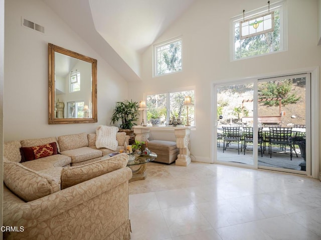 living area featuring a wealth of natural light, visible vents, and high vaulted ceiling