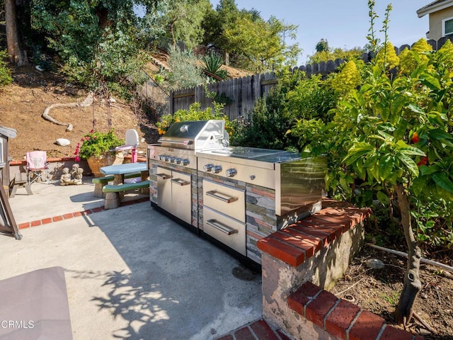 view of patio / terrace with a grill, fence, and an outdoor kitchen