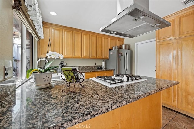 kitchen featuring visible vents, tile patterned floors, freestanding refrigerator, white stovetop, and extractor fan