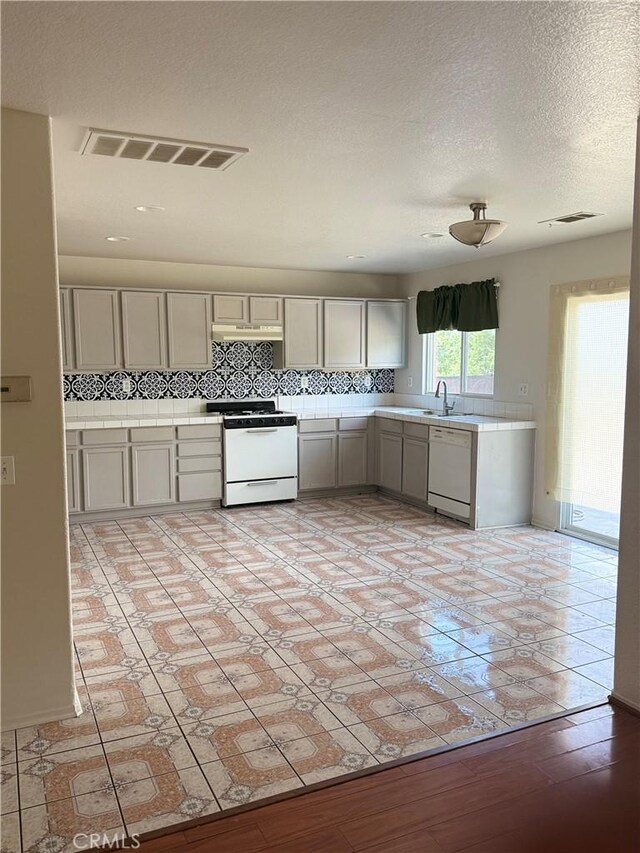 28764 Avalon Ave, Moreno Valley, CA 92555 - kitchen featuring white appliances, tile counters, under cabinet range hood, tasteful backsplash, and gray cabinets