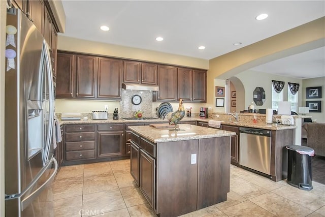 31973 Wildwood Ct, Temecula, CA 92592 - kitchen featuring appliances with stainless steel finishes, arched walkways, light stone countertops, dark brown cabinetry, and recessed lighting