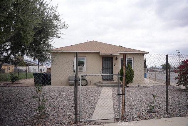 bungalow featuring roof with shingles, a gate, a fenced front yard, and stucco siding
