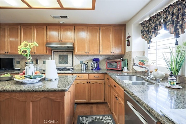 kitchen with light stone counters, visible vents, a sink, under cabinet range hood, and appliances with stainless steel finishes