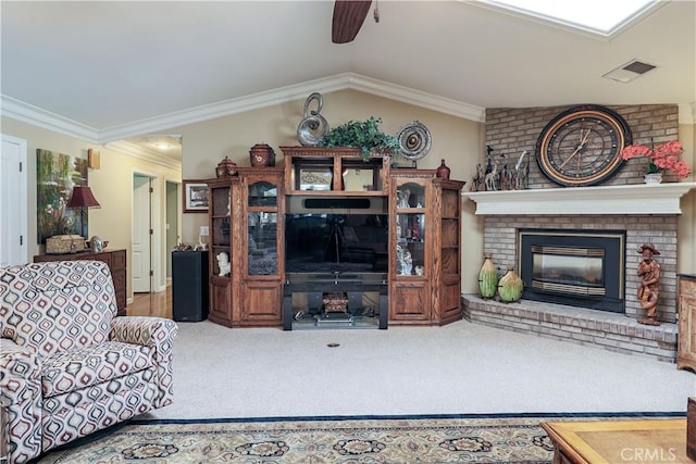 carpeted living area with visible vents, a ceiling fan, crown molding, lofted ceiling, and a brick fireplace