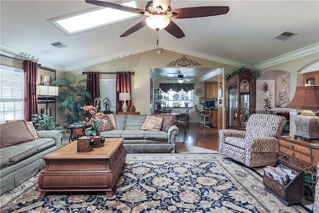 living area with visible vents, crown molding, a ceiling fan, and wood finished floors