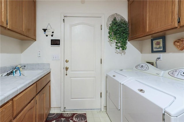 clothes washing area featuring washing machine and clothes dryer, cabinet space, and a sink