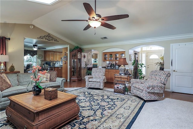 living area with visible vents, a ceiling fan, arched walkways, and vaulted ceiling