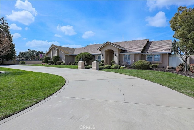 ranch-style home with stucco siding, curved driveway, a front yard, and a tiled roof