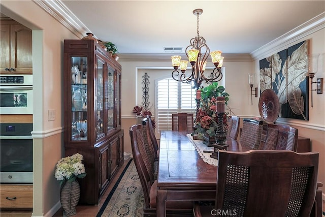 dining room featuring an inviting chandelier, crown molding, and visible vents