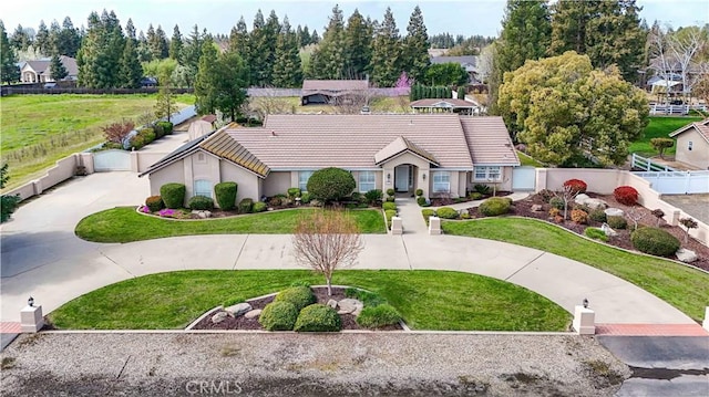 view of front of house with a tiled roof, stucco siding, a front lawn, and fence