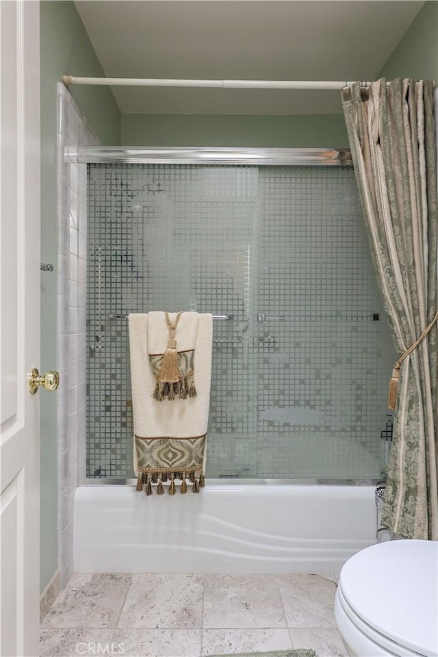 bathroom with toilet and bath / shower combo with glass door