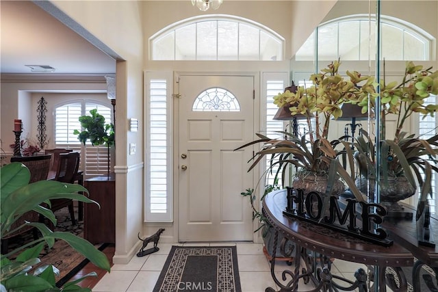 entrance foyer featuring light tile patterned floors, visible vents, baseboards, and a towering ceiling