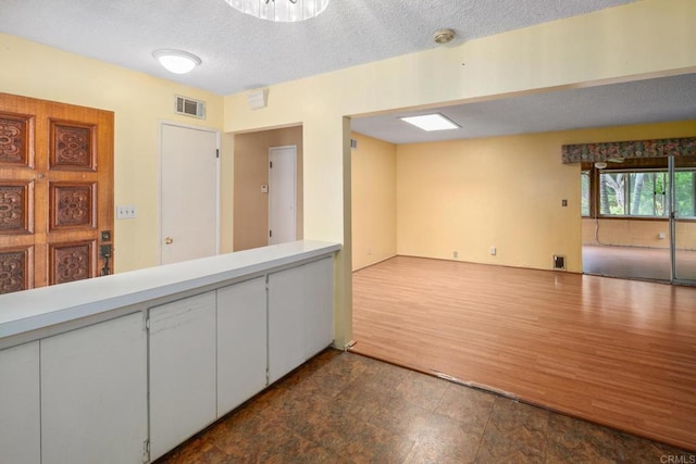interior space featuring a textured ceiling, open floor plan, light countertops, and visible vents