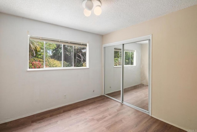 unfurnished bedroom with multiple windows, a textured ceiling, and wood finished floors