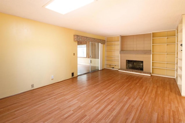 unfurnished living room featuring light wood-style floors and a tile fireplace