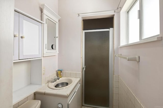 full bath featuring a wainscoted wall, vanity, toilet, and a shower stall