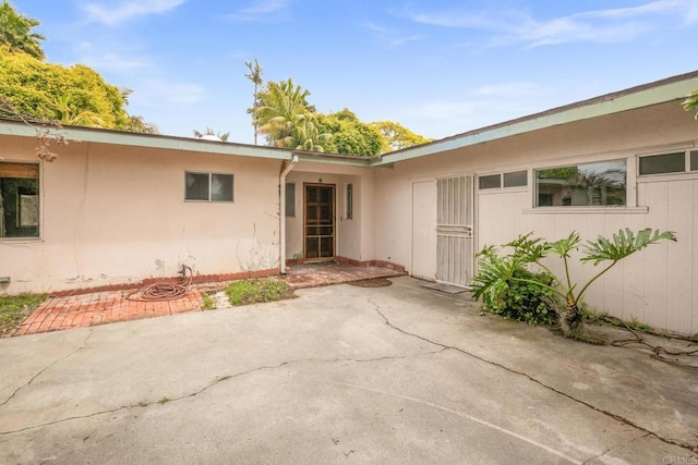 entrance to property featuring a patio and stucco siding