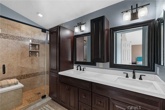 full bath featuring a sink, vaulted ceiling, a stall shower, and double vanity
