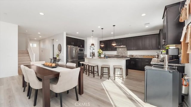dining space featuring light wood finished floors, recessed lighting, and stairway