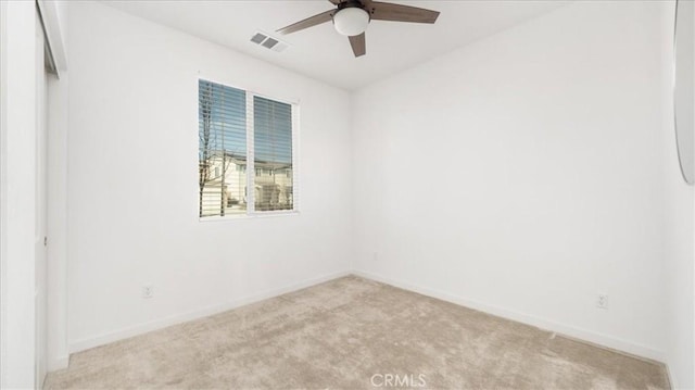 empty room featuring light colored carpet, ceiling fan, and baseboards