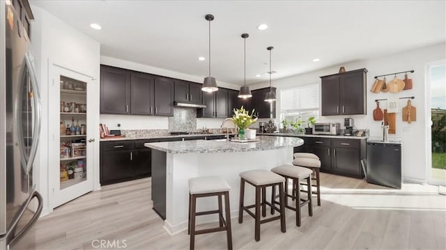 35461 Alexandria Way, Beaumont, CA 92223 - kitchen with freestanding refrigerator, light wood-style floors, a kitchen breakfast bar, a center island with sink, and recessed lighting