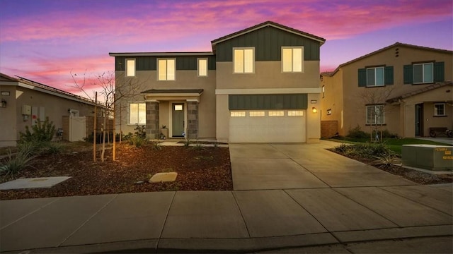 view of front of home with driveway, an attached garage, stucco siding, and board and batten siding