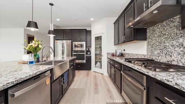 35461 Alexandria Way, Beaumont, CA 92223 - kitchen featuring appliances with stainless steel finishes, wall chimney range hood, a sink, light wood-type flooring, and decorative backsplash