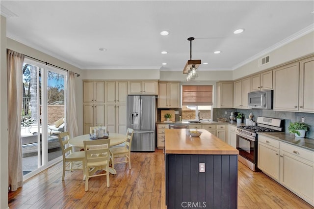 11 Spring View Way, Rancho Santa Margarita, CA 92688 - kitchen with appliances with stainless steel finishes, cream cabinetry, ornamental molding, a center island, and backsplash