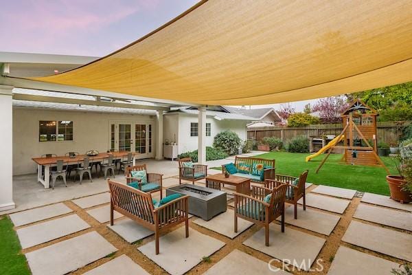 view of patio with an outdoor living space with a fire pit, a playground, french doors, and fence