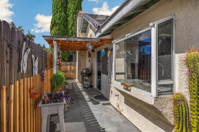 view of patio featuring fence and a grill