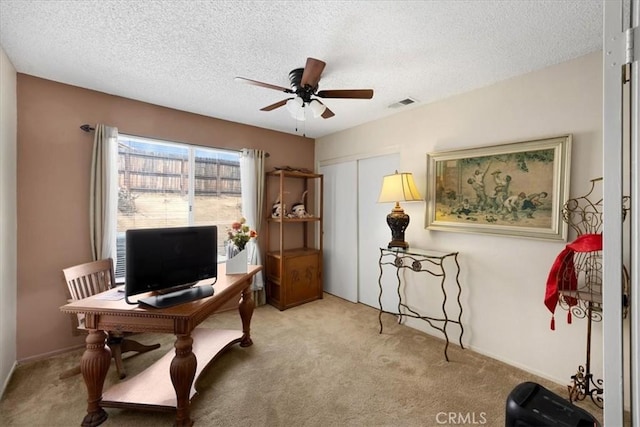 carpeted office space with visible vents, a textured ceiling, and ceiling fan