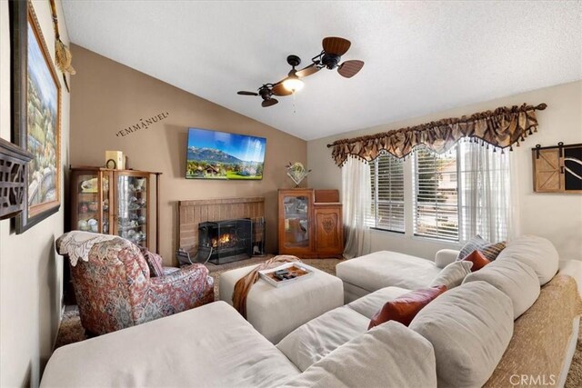 living room featuring vaulted ceiling, a fireplace, and ceiling fan