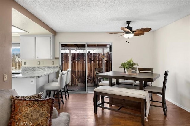 dining space featuring a ceiling fan, dark wood-style floors, and a textured ceiling