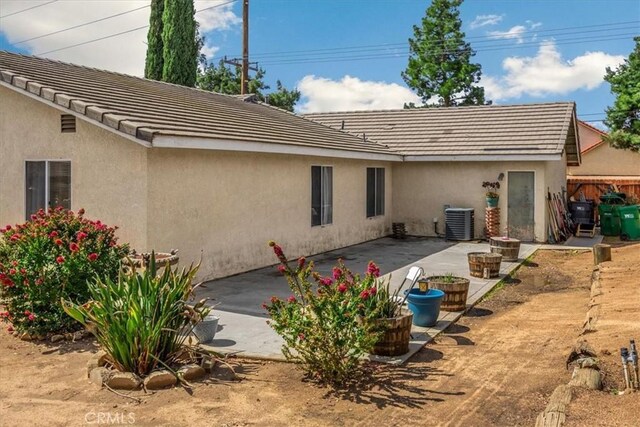 back of house with stucco siding, a patio, central AC, and a tile roof