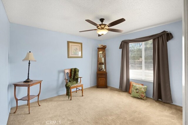 living area with light carpet, a textured ceiling, and ceiling fan