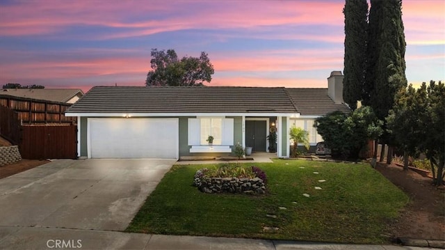 single story home with a tile roof, concrete driveway, a front yard, a chimney, and a garage