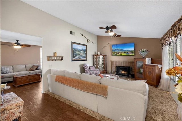 living area featuring a brick fireplace, lofted ceiling, ceiling fan, and wood finished floors