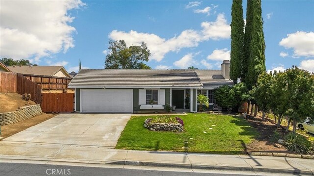 single story home with fence, a tile roof, concrete driveway, a front yard, and a garage