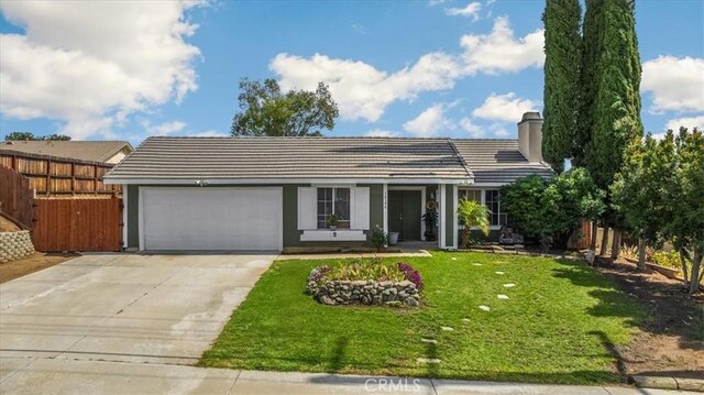 view of front of property with a garage, concrete driveway, a front yard, and fence