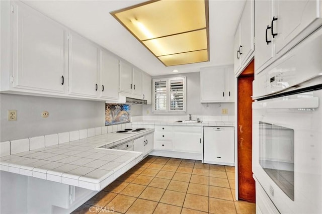 kitchen featuring a sink, white appliances, white cabinets, and tile countertops